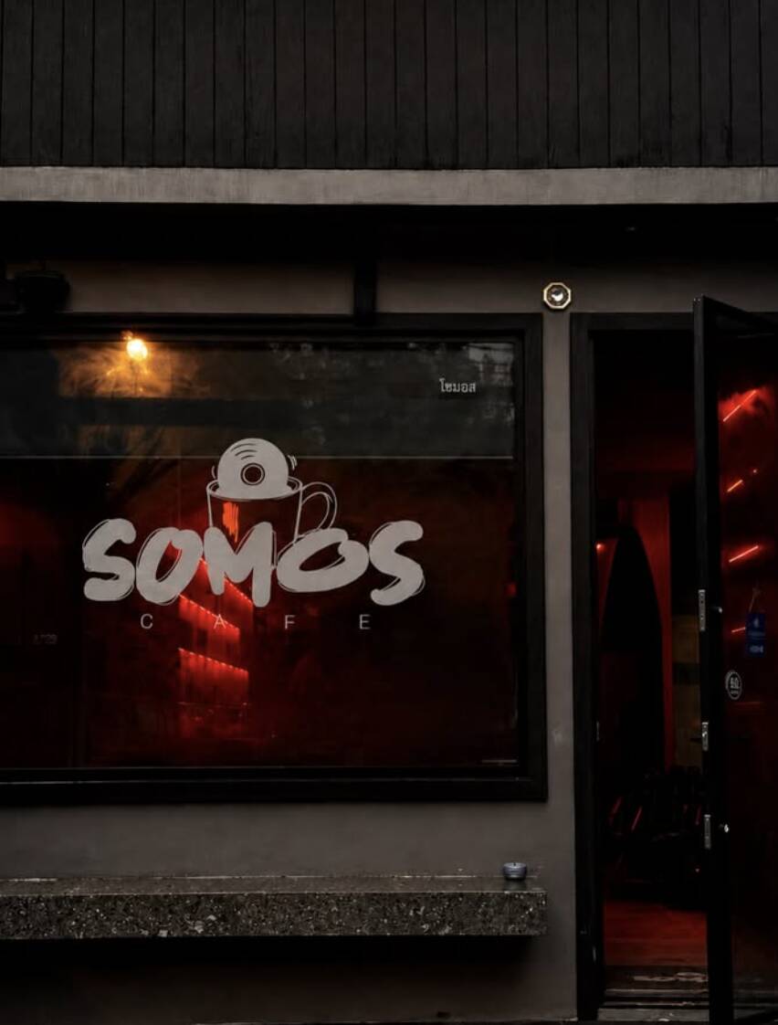 The Somos storefront window glowing red at night